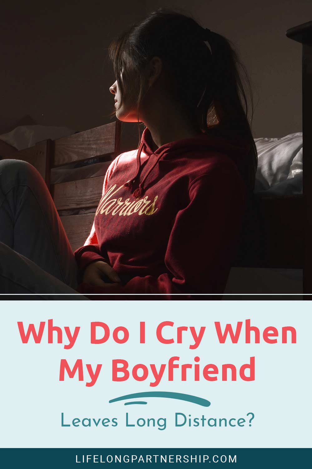 Girl wearing red hoodie sitting on her bed - Why Do I Cry When My Boyfriend Leaves Long Distance?